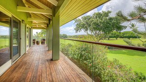 Un espacio al aire libre cubierto con terraza de madera, puertas de vidrio y vistas a un paisaje verde.