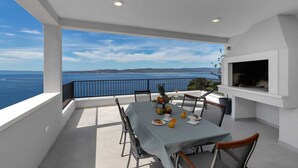 A balcony with a table set for breakfast, overlooking a scenic coastal view. - Villa Seraphine with Pool (Brela)