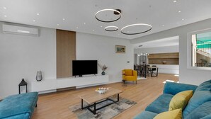 A modern living room with a flat-screen TV, a sofa, a coffee table, and a dining area with chairs and a table. - Villa Seraphine with Pool (Brela)