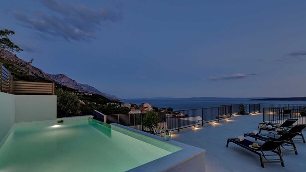 A rooftop pool with lounge chairs and a view of the sea and mountains. - Villa Seraphine with Pool (Brela)