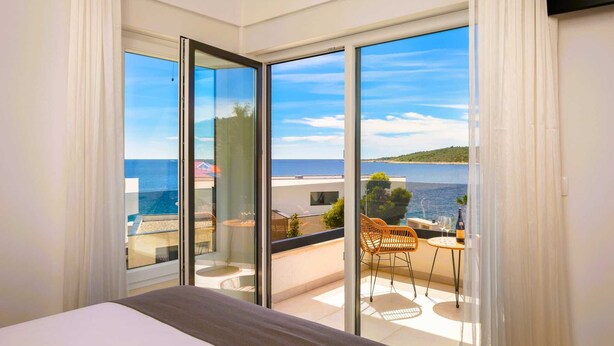 Habitación de hotel con un amplio ventanal corredero que da a un balcón con vistas al mar.