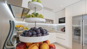 A modern kitchen with a fruit display, stainless steel appliances, and white cabinetry. - Villa Azul Grande with Heated Pool (Brela)