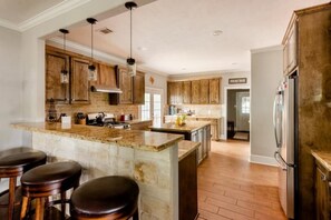 A spacious kitchen with a large island, wooden cabinets, and a stainless steel refrigerator. - 4BR/4.5Bath Spacious Family Home +Walk to KyleField (College Station)