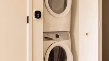 A compact laundry room with two stacked washing machines, a control panel, and a digital display.