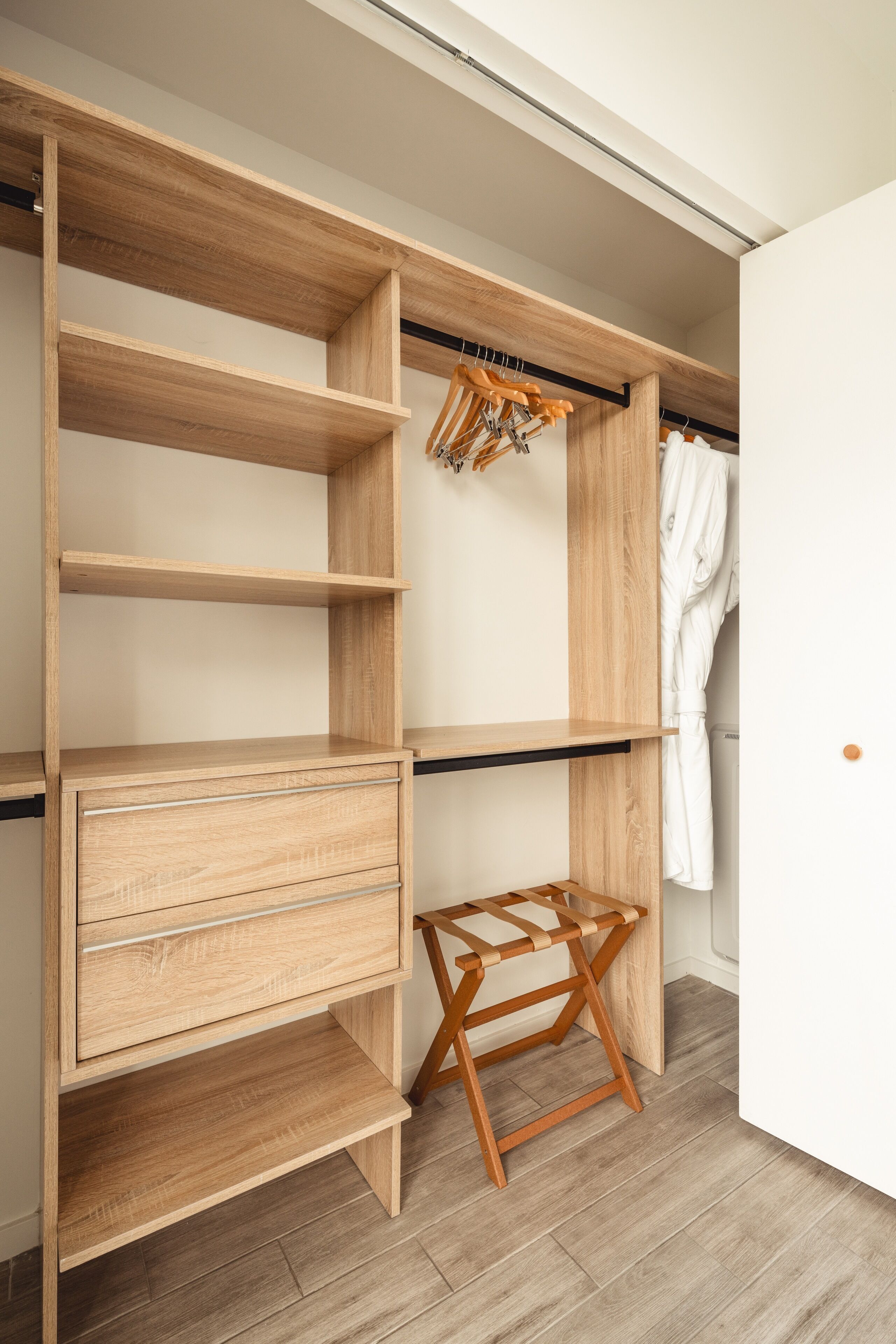 A walk-in closet with multiple wooden shelves and a hanging rack.