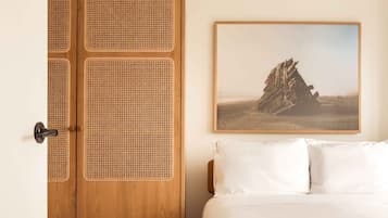 A bedroom with a wooden wardrobe, a bed with white bedding, and a framed picture on the wall.