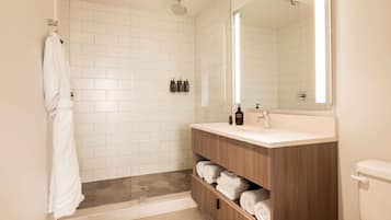 A modern bathroom with a glass-enclosed shower, a wooden vanity with a mirror, and a toilet.