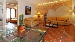Un saló amb una taula de cafè de vidre, un sofà, un cactus i una paret de pedra.