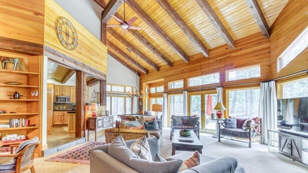 A spacious living area with wooden beams, a fireplace, and large windows. - Pools, Private Hot Tub & Pool Table. Upscale Lodge (Sisters)