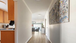 Un pasillo con armarios de madera, una zona de cocina y un cuadro abstracto grande en la pared.
