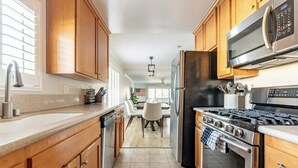 Una cocina con armarios de madera, electrodomésticos de acero inoxidable y piso de baldosas.