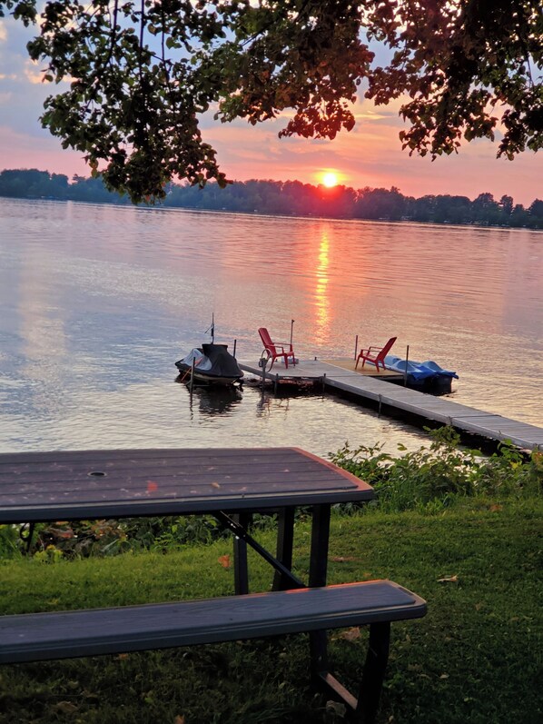 Une vue sur le lac avec un quai, un bateau et une table de pique-nique.