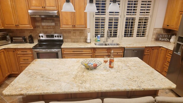 A kitchen with wooden cabinets, a granite countertop, a built-in oven, a sink, and a dining area with chairs. - Well-equipped 3BR/3BA with large common space in the heart of Historic Downtown (New Iberia)