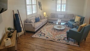 A living room with two sofas, a coffee table, a rug, and a TV mounted on the wall. - Well-equipped 3BR/3BA with large common space in the heart of Historic Downtown (New Iberia)