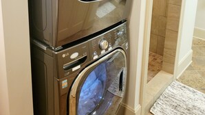 A stacked washer and dryer unit with a control panel, a sensor dry feature, and a tiled floor. - Well-equipped 3BR/3BA with large common space in the heart of Historic Downtown (New Iberia)