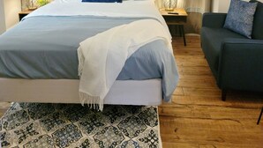 A bedroom with a bed, a ceiling fan, a nightstand, a lamp, a sofa, and a patterned rug. - Well-equipped 3BR/3BA with large common space in the heart of Historic Downtown (New Iberia)