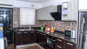 Una cocina moderna con armarios de madera oscura, horno empotrado, microondas y estufa a gas.