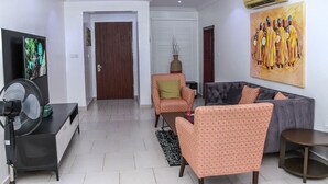 Una sala de estar con sofá, sillones, televisor y aire acondicionado.