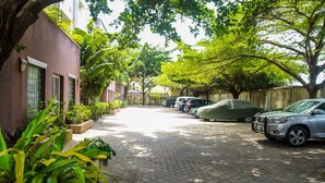 Un camino de adoquines con coches estacionados y exuberante vegetación.