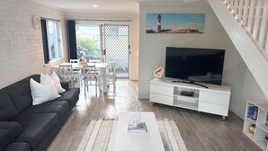 Ein modernes Wohnzimmer mit Sofa, Fernseher und Essbereich.