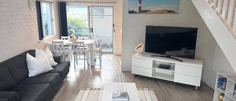 En moderne stue med sofa, TV og spiseplads.
