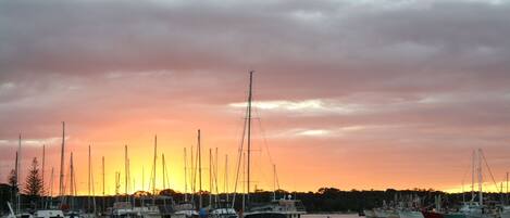 A marina with multiple boats docked under a sunset sky.