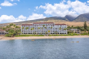 A hotel with multiple floors, a beach in the background, and kayaks on the water. - LUXURY OCEAN and BEACH FRONT studio in Lahaina Shores.  Sunset ocean views! (Lahaina)
