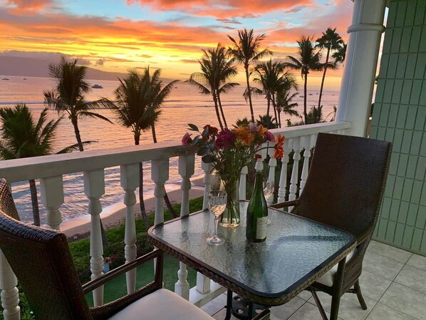 A balcony with a table, chairs, and a vase of flowers.