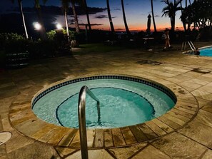 A circular hot tub with a metal ladder, surrounded by a tiled patio area.