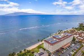 A coastal hotel with a parking lot, a beach, and a view of the ocean with boats. - Lahaina Shores Ocean Front Luxury Condo 525 (Lahaina)