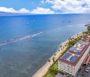 A coastal hotel with a beach view, solar panels on the roof, and a clear blue sea with boats. - LUXURY OCEAN and BEACH FRONT studio in Lahaina Shores.  Sunset ocean views! (Lahaina)