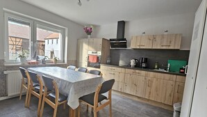 A compact kitchen with a dining table and chairs, wooden cabinets, and a window with a view of the outside. - Apartment Fulda 65m² up to 6 pers. (Fulda)