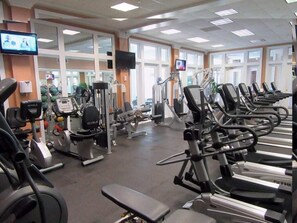 A gym with various exercise machines, a television, and large windows. - A409 King/Twin bunk & Full bed/ Sofa Sleeper-Beach Front-Pools - sleeps 8 (Gulf Shores)