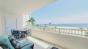 Un balcón con vista a la playa, una mesa de comedor y un sofá.