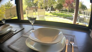 Une table à manger avec un ensemble d’assiettes blanches, un verre à vin et des couverts disposés sur un set de table foncé.