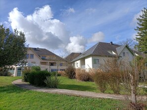 Um edifício residencial com um caminho no jardim, uma placa indicando que é um hotelaria residencial, e um céu limpo.