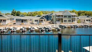 A marina with boats docked, a wooden deck, and houses with balconies in the background. - Kayak Shack: Waterfront, 2nd Floor, Boat Dock, In the Heart of Downtown (Sylvan Beach)