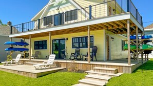 A two-story house with a covered deck, outdoor seating, and a boat storage area. - Kayak Shack: Waterfront, 2nd Floor, Boat Dock, In the Heart of Downtown (Sylvan Beach)