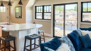 A kitchen with a central island, bar stools, and pendant lighting. - Kayak Shack: Waterfront, 2nd Floor, Boat Dock, In the Heart of Downtown (Sylvan Beach)