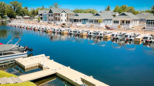 A marina with multiple docked boats and a row of houses in the background. - Kayak Shack: Waterfront, 2nd Floor, Boat Dock, In the Heart of Downtown (Sylvan Beach)