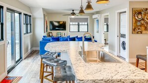 A modern kitchen with a central island, bar stools, and pendant lighting. - Kayak Shack: Waterfront, 2nd Floor, Boat Dock, In the Heart of Downtown (Sylvan Beach)