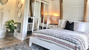 Een slaapkamer met een bed, nachtkastjes, een spiegel en een kledingkast.