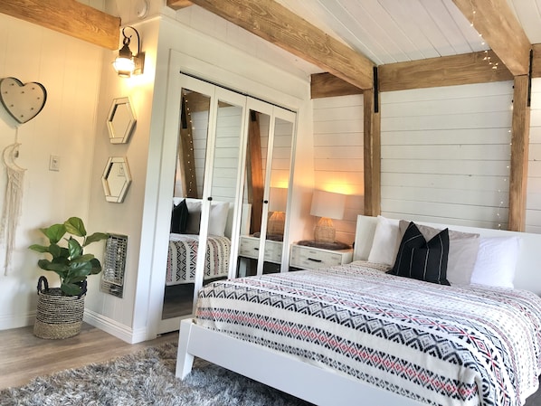 Une chambre à coucher avec un lit, des tables de chevet, un miroir et une armoire.