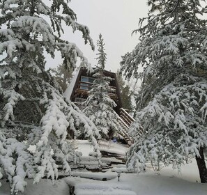 A snow-covered building with a wooden staircase leading up to a door.