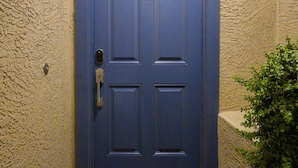A blue door with a doorknob and a welcome mat with a decorative pattern.