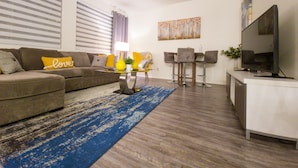 A modern living room with a sofa, a coffee table, a TV, and a painting on the wall.