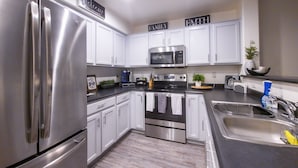 A modern kitchen with stainless steel appliances, white cabinets, and a central island with a sink and countertop.