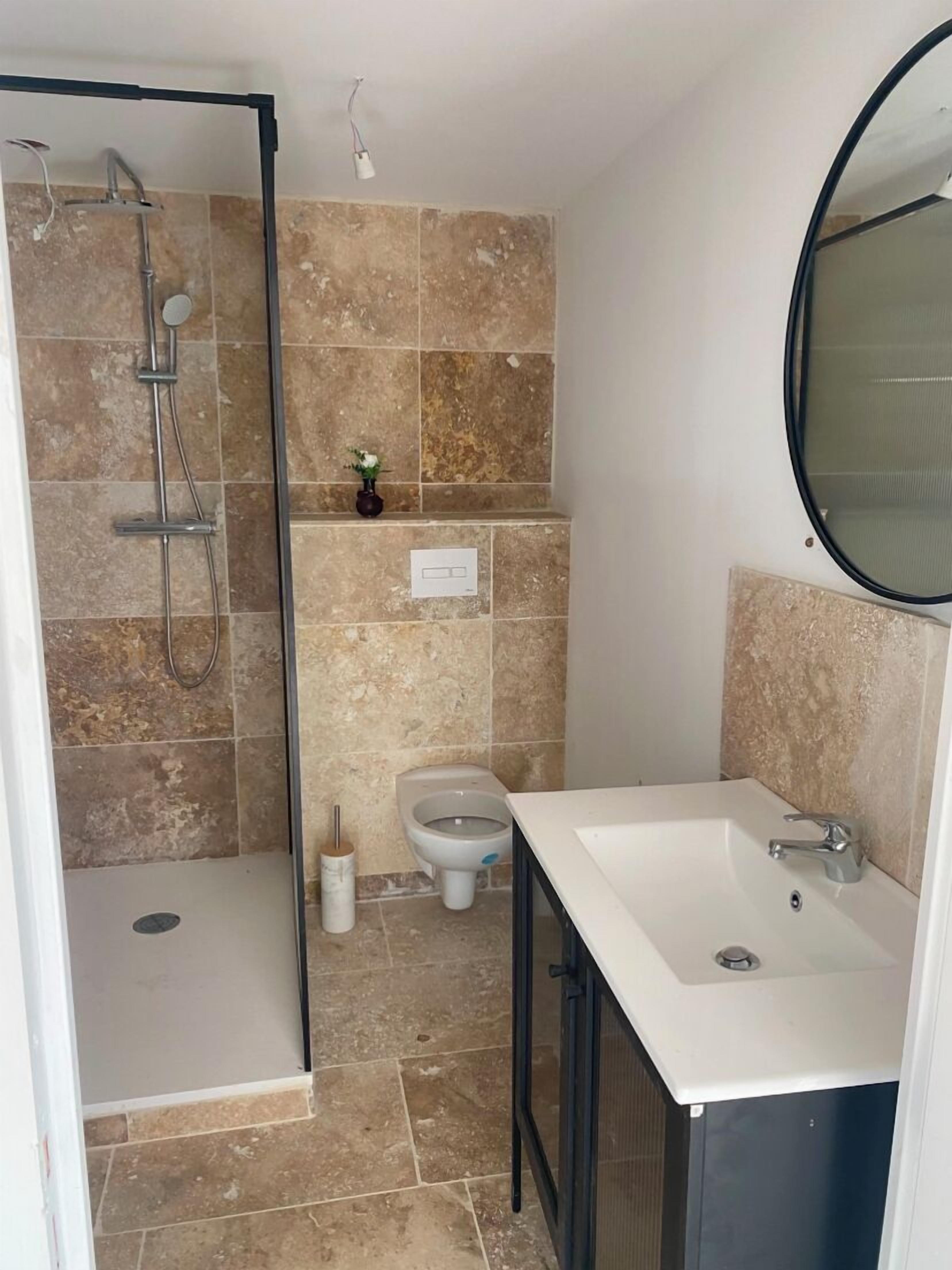 A bathroom with a shower, toilet, sink, and mirror.