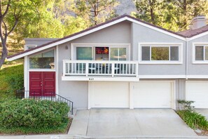 Une maison à deux étages avec une porte rouge, un balcon et un garage.