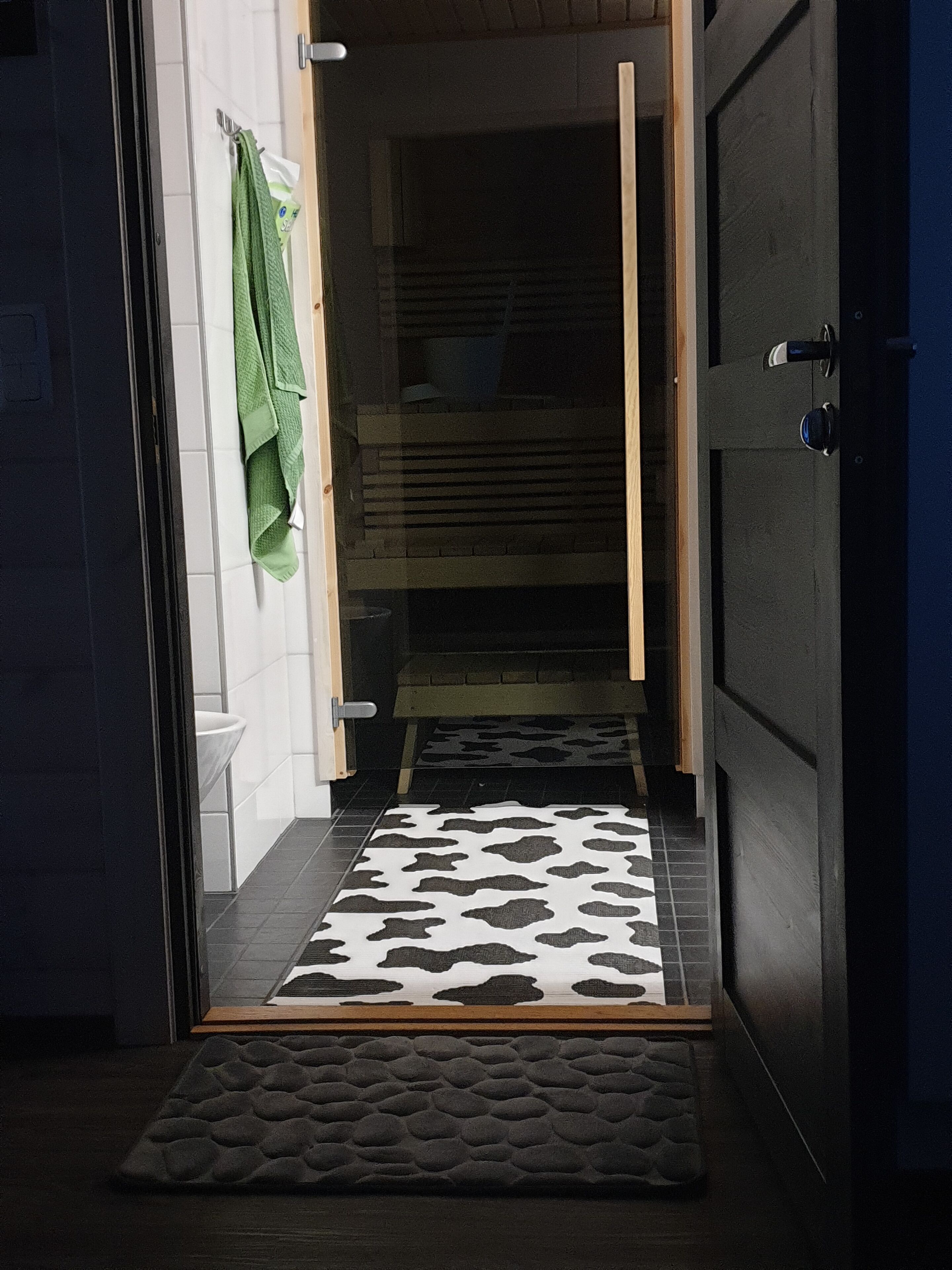Un baño con ducha, una toalla colgada en la pared y un tapete estampado en el suelo.